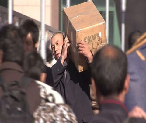 Beijing, China; camera tracks man carrying big box through crowd of pedestrians Stock-Footage 86745185
