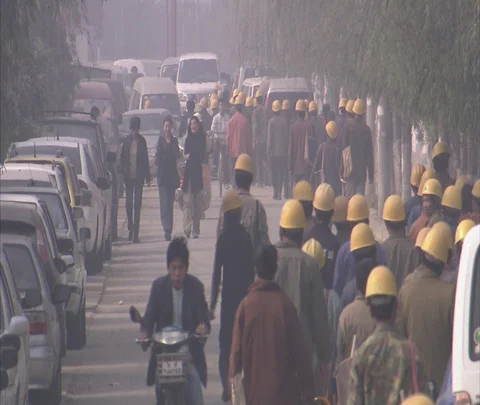 Beijing, China; MS crowd of workers in yellow hard hats walking towards traffic Stock Footage 86744033