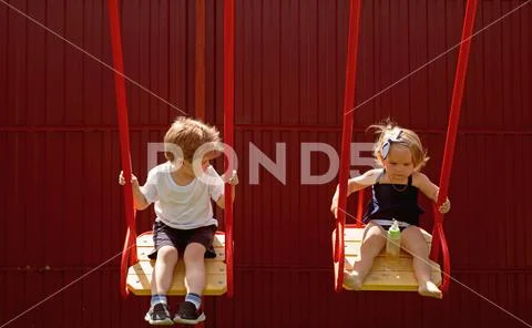 Being active outside. Small children with blond hair on swing. Girl and boy Stock Photos
