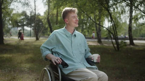 Being in the public park, a handsome disabled blonde man in a wheelchair is Stock Footage 173836141