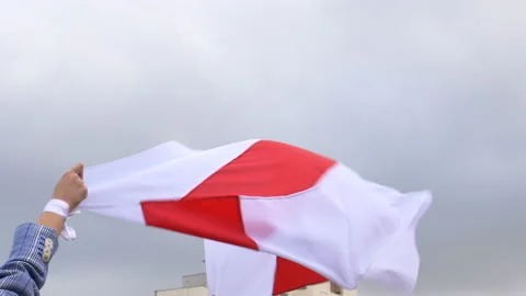 Belarusian flag waving in the wind held by a hand with a white wristband Stock Footage