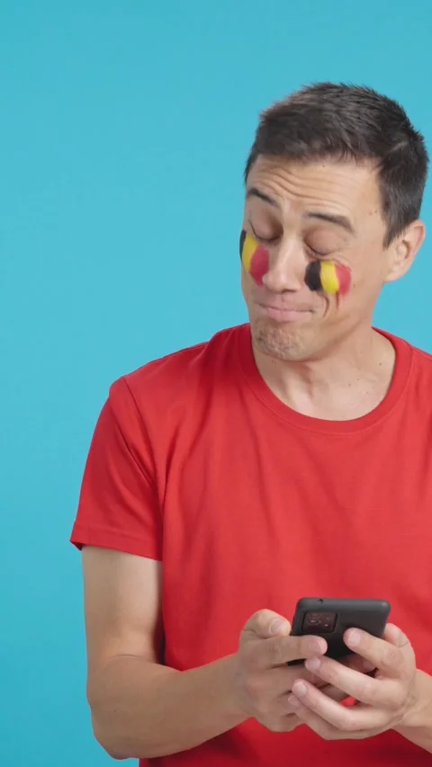 Belgian supporter looking at his mobile smiling and showing it. Stock Footage 257310168