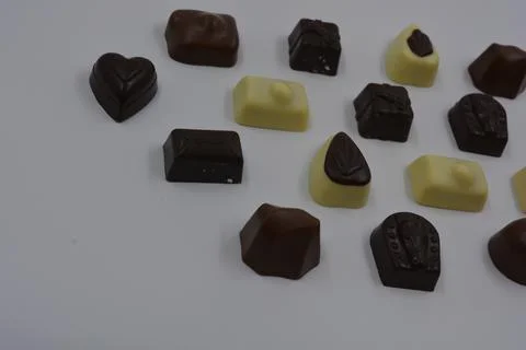 Belgian sweets made of black, milk, white chocolate are on a white plastic. Stock Photos