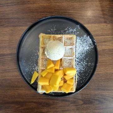 Belgian waffle with fresh mango and vanilla ice cream Stock Photos