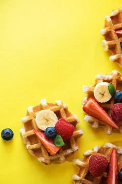 Belgian waffles with berries on a yellow background. Top view and copy space. Stock Photos