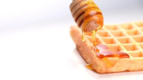 Belgian waffles with pouring honey closeup over white background Stock Footage