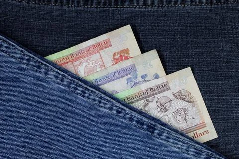 Belizean banknotes of different denomination between blue denim fabric Stock Photos