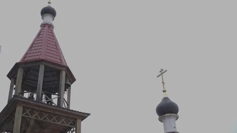 A bell-ringer on the bell tower of a wooden Orthodox church rings the bells Stock Footage 301276880