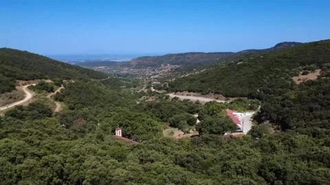 Bell tower with cross emerging from dense Mediterranean forest in Greece Vídeo Stock 317295614