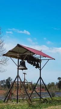 Bell tower structure with multiple bells under a red roof against blue sky Stock Photos