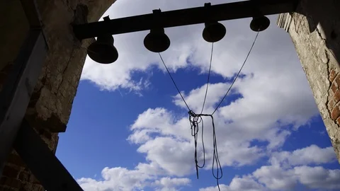 Bells on the background of blue sky with clouds. Bells of various sizes hang in Stock Footage 97535789