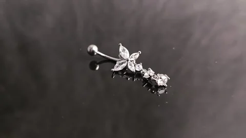 Belly button earrings with stones and a pendant in the shape of cannabis leaves. Stock Footage 309186286