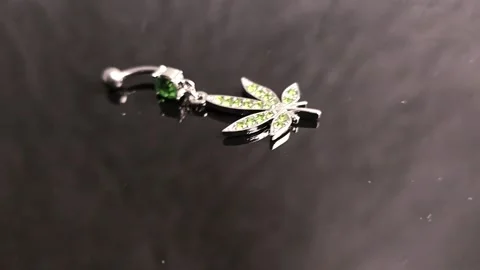 Belly button earrings with stones and a pendant in the shape of cannabis leaves. Stock Footage 309186598