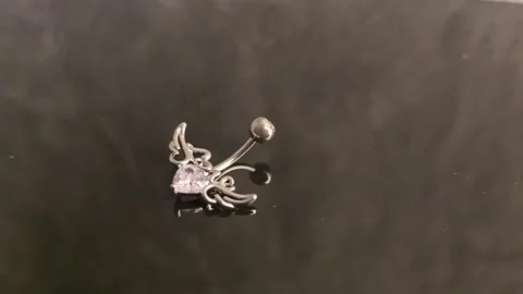 Belly button earrings with stones and a pendant in the shape of cannabis leaves. Stock Footage 309186798