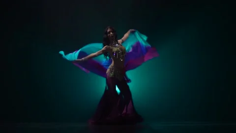 Belly dancer girl continue dance uses fans. Smoke background. Slow motion Video stock 105033128