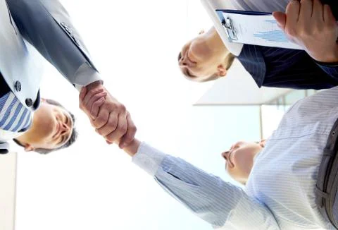 Below angle of successful associates handshaking after striking deal Stock Photos