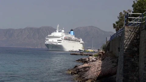 Below cliffs at water's edge, cruise ship harbored in background Stock Footage 83076268
