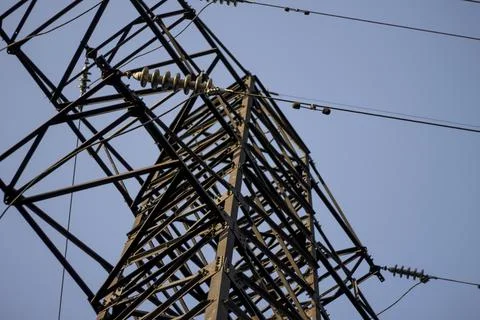 Below, a high voltage power line on a sunny day with a blue sky background, sele Stock Photos