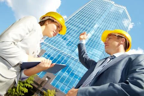 Below view of confident architect pointing at modern office building and looking Fotos de archivo