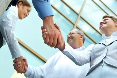Below view of rows of happy partners handshaking outdoors on background of moder Stock Photos
