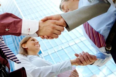 Below view of rows of happy partners handshaking outdoors on background of moder Stock Photos