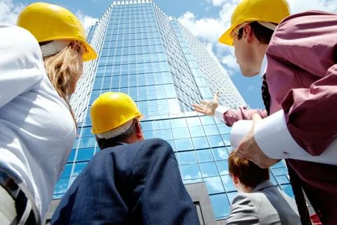 Below view of several architects looking at modern office building against cloud Fotos de archivo