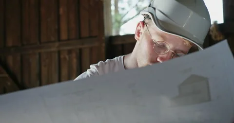 From below young man in hardhat thinking and making notes on draft while working Stock Footage 141463591