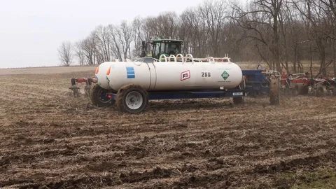 Belted John Deere tractor turning while using planter and fertilizer tanks Stock Footage 129364073