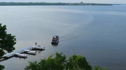 BEMIDJI, MN - 2 JUN 2023: Pontoon boat approaches a dock on the lake. Stock Footage 251756874