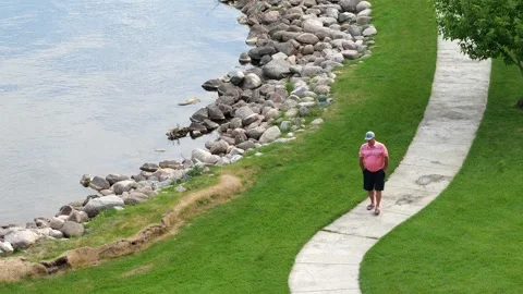 BEMIDJI, MN - 3 JUN 2023: Senior man enjoys walking at the lake. Stock Footage 251756880