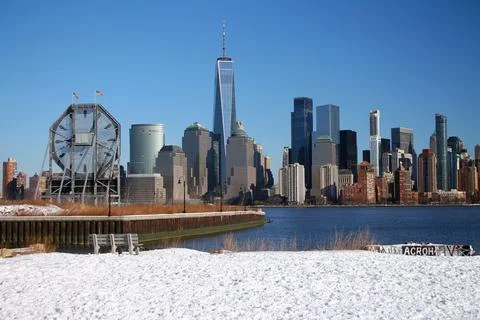 The bench and the big clock looking at downtown Manhattan with the snow on th Stock Photos