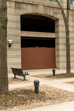 Bench and wall under an archway near a street in an urban area with trees a.. Stock Photos