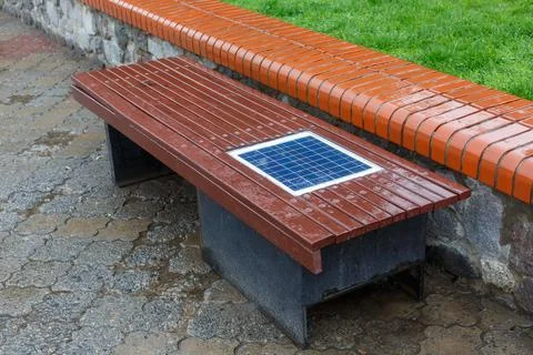 A bench with a built-in solar panel for charging phones. Stock Photos