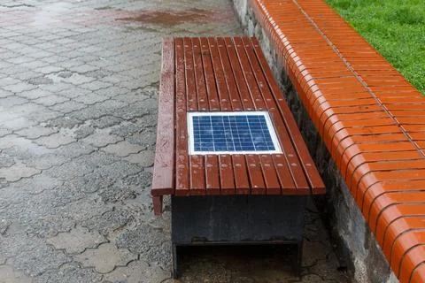 A bench with a built-in solar panel for charging phones. 스톡 사진