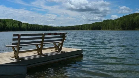 Bench on a dock on a northern lake. Small wave lap against the dock. Stock Footage 155342051