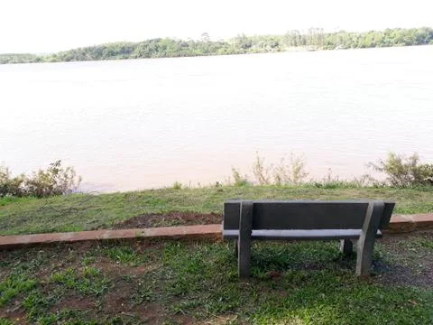 Bench facing the river, to sit and relax Stock Photos