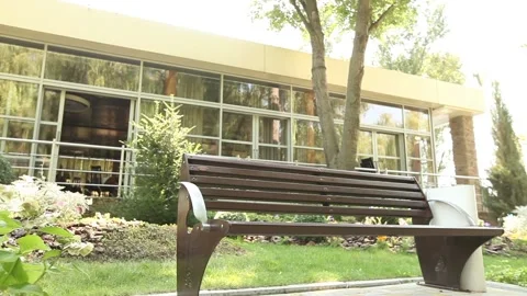 A bench in front of a restaurant in the park, a modern building Vídeos de archivo 94601712