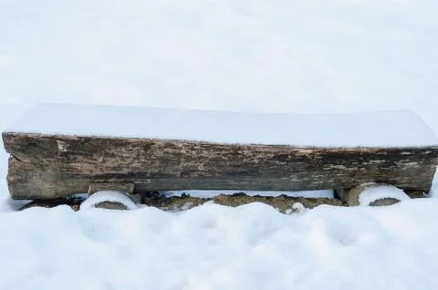 Bench made from tree trunk  covered  with snow  in park during winter Stock Photos