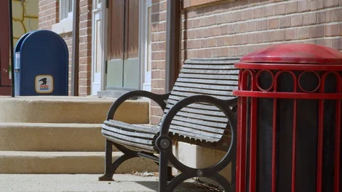 Bench outside a building in a small town on a sunny early spring day. 4k60p Stock Footage 128847999