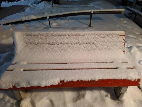 Bench outside completely covered with snow at night Stock Photos