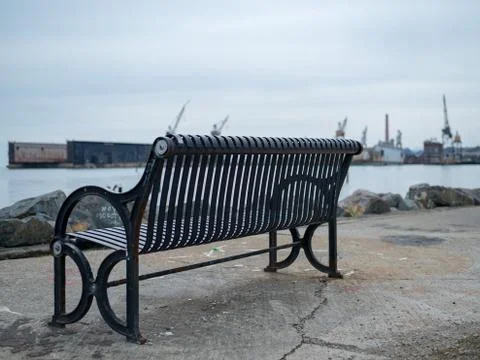 Bench overlooking bay and construction yard Stock Photos