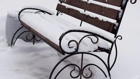 A bench in a park under a layer of snow in winter nature. Slow motion Stock-Footage 291776818