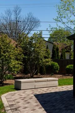 Bench placed in a backyard garden with trees and green grass during sunny day Фото