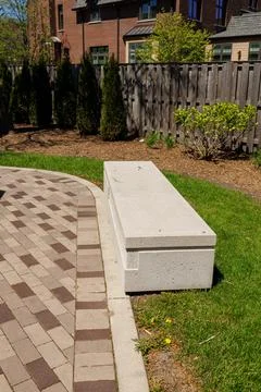 Bench placed on a walkway surrounded by grass and plants in a residential a.. Fotos Stock