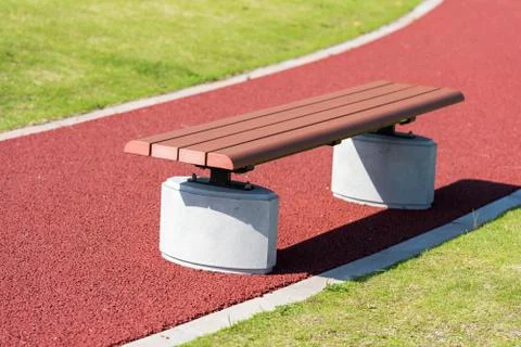 A bench on a red pathway in the park.  Stock Photos