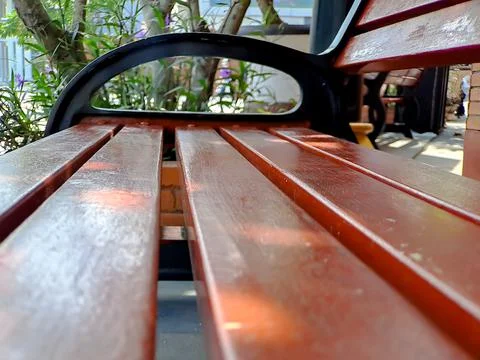Bench rest area made of black brown wood and iron, bright blue sky in the gar Stock Photos