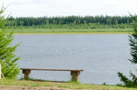 Bench for rest of tree is on the cliff North of the river Vilyui with taiga f Stock Photos