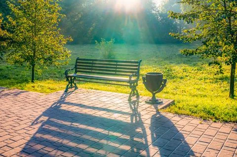 Bench is sitting on a brick path in a park Stock-Fotos