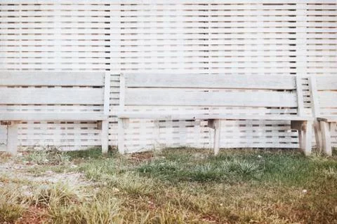 Bench stand at a wall from white colored boards at sunset Stock Photos
