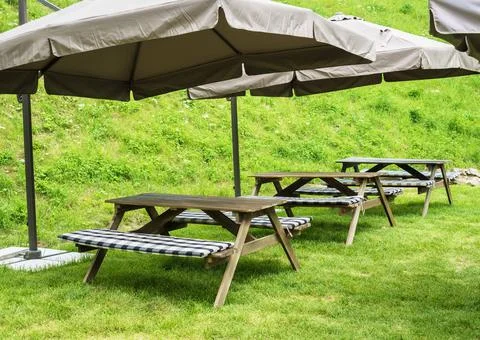 Bench with a table under a large umbrella on green grass Stock Photos